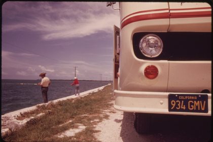 A retired couple fishing beside their travel trailer