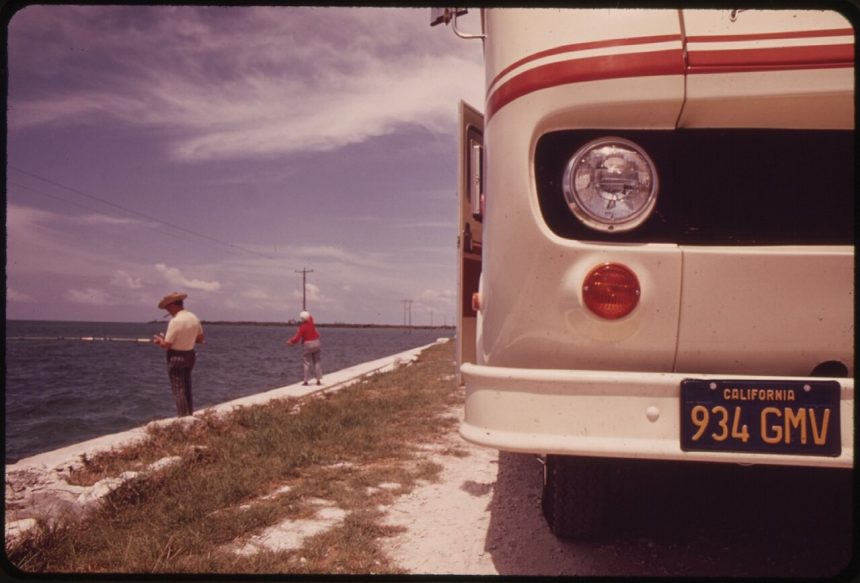 A retired couple fishing beside their travel trailer